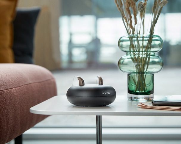 Modernes Hörsystem auf einem Tisch in einer Wohnumgebung, dargestellt im Alltagskontext.