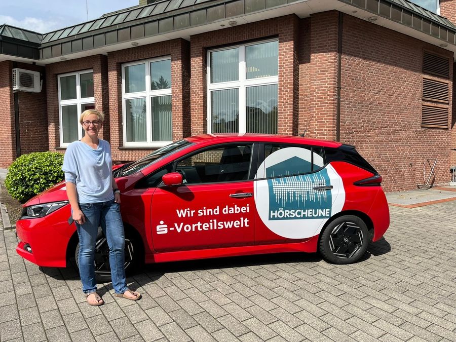 Zwei Personen stehen vor einem Servicefahrzeug mit Firmenbeschriftung und halten Abstand zueinander im Außenbereich.